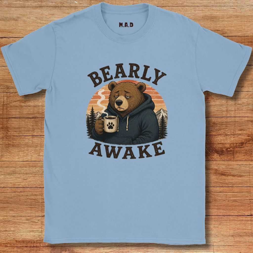 Light blue t-shirt with a bear graphic and 'BEARLY AWAKE' text on a wooden surface