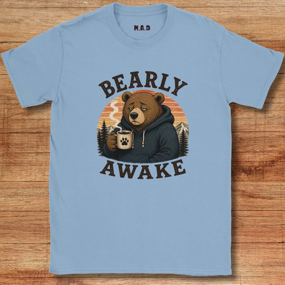 Light blue t-shirt with a bear graphic and 'BEARLY AWAKE' text on a wooden surface