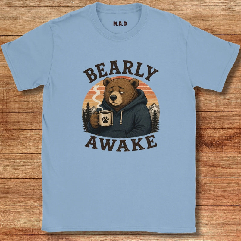 Light blue t-shirt with a bear graphic and 'BEARLY AWAKE' text on a wooden surface