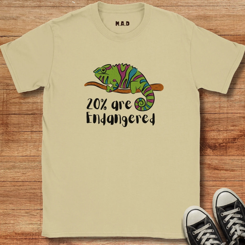Beige t-shirt with a chameleon graphic and text '20% are Endangered' on a wooden surface.
