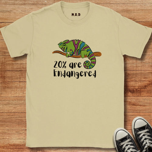 Beige t-shirt with a chameleon graphic and text '20% are Endangered' on a wooden surface.