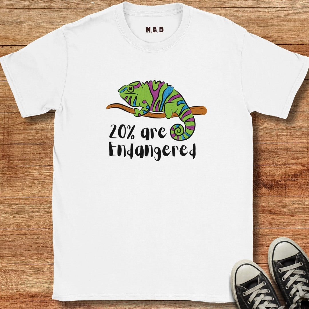 White t-shirt with a chameleon graphic and text '20% are Endangered' on a wooden surface.