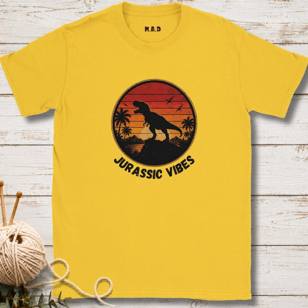 Yellow t-shirt with dinosaur graphic and 'Jurassic Vibes' text on a wooden surface.