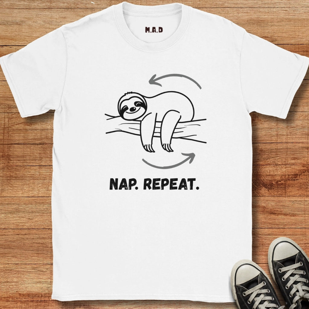 White t-shirt with a sloth graphic and 'Nap. Repeat.' text on a wooden surface.