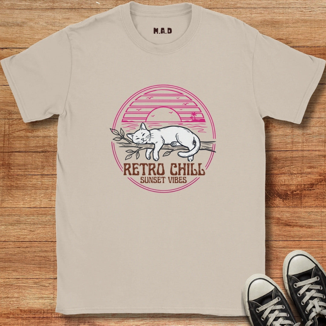 Beige t-shirt with a cat graphic and 'Retro Chill Sunset Vibes' text on a wooden surface.
