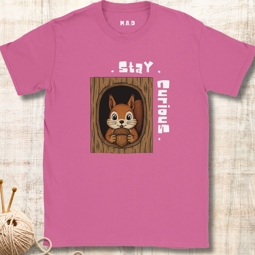 A pink short-sleeve t-shirt with a graphic of a curious squirrel in a tree hole, featuring the text 'Stay Curious' 