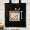 Black tote bag with a cat illustration and 'Stay Curious' text on a wooden surface.