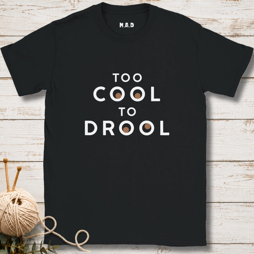 Black t-shirt with 'Too Cool to Drool' text on a wooden surface